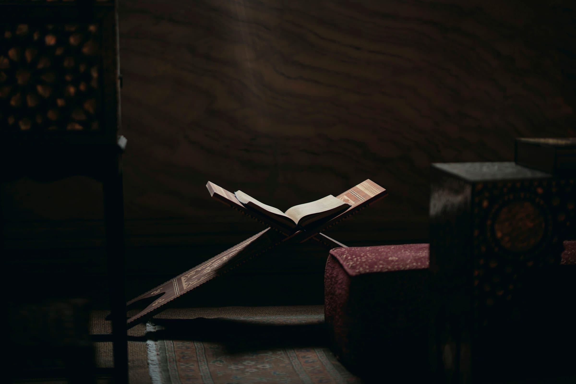 An open Qur'an resting on a wooden rehal stand